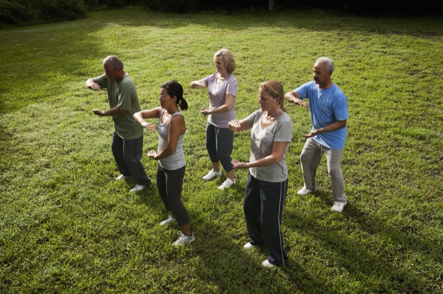 A tai chi class practicing together outdoors